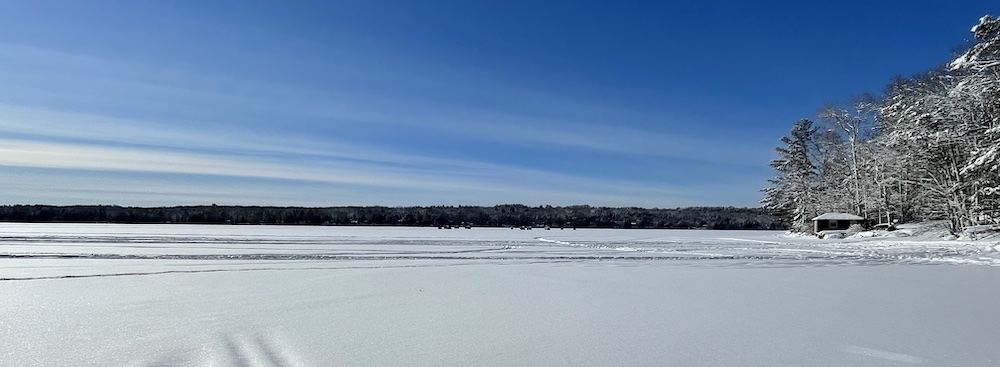 image of a snow covered lake, blue skies and snow covered trees