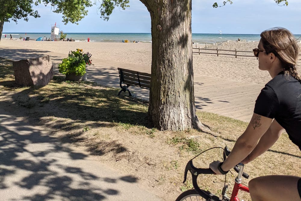 woman on a red bike riding along the beach front path
