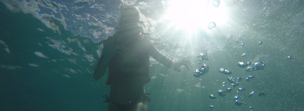 woman underwater snorkelling with sun shining
